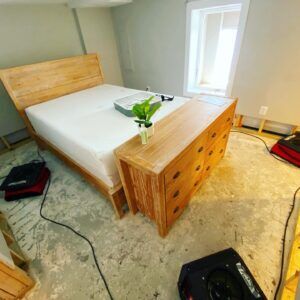 Bedroom with exposed flooring and drying equipment after water damage restoration